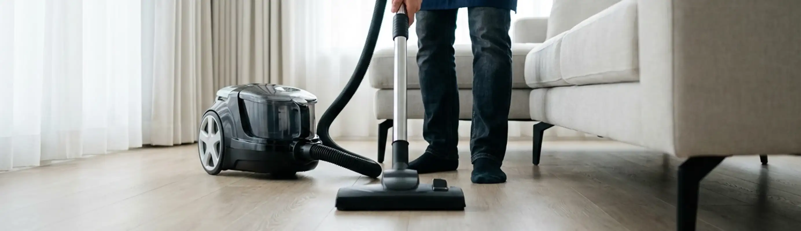 Professional house cleaner vacuuming a living room floor with a canister vacuum cleaner, Reno, NV.