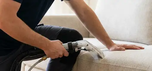 Professional upholstery cleaner deep-cleaning a fabric sofa with a handheld extraction tool, Reno, NV.